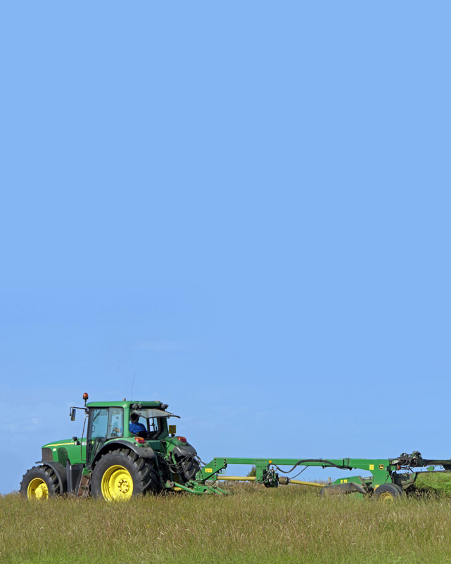 John Deere Traktor und Mäher beim Mähen von Gras für Silage